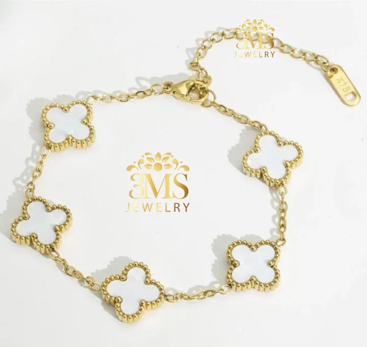 Gold bracelet with five white four-leaf clover charms and chain links on white background