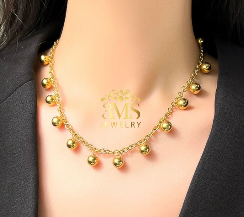 "18K gold beaded choker necklace in a titanium steel with gold vermeil—on a neck wearing full detail"
