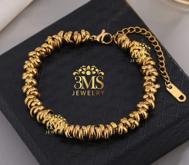 Elegant gold-tone bracelet with twisted beads and adjustable lobster clasp on black quilted box