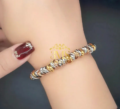 Close-up of wrist wearing a gold and silver twisted link bracelet with a dark background