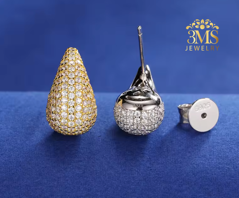 Teardrop-shaped earrings in gold and silver on a blue background with 3MS Jewelry logo.