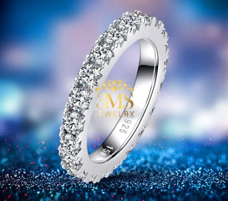 Silver 925 eternity ring with round-cut moissanite stones on glittery blue surface