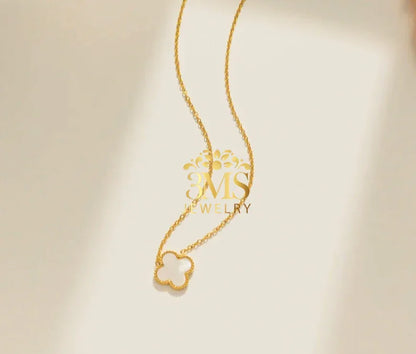 Elegant gold necklace with a clover-shaped pendant on a light beige background