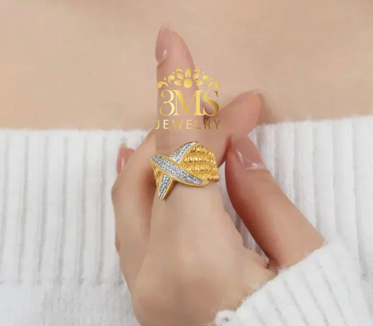 Close-up of a hand wearing a gold and silver textured statement ring with diamonds