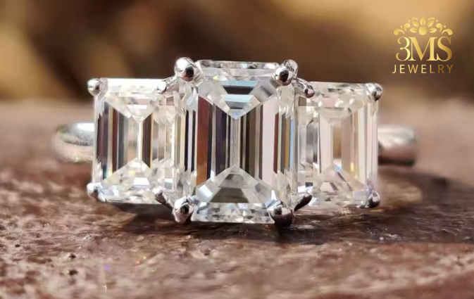 "Lab diamond emerald-cut engagement ring in three-stone design and 14K yellow gold settings—a close-up view."