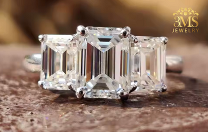 "Lab diamond emerald-cut engagement ring in three-stone design and 14K yellow gold settings—a close-up view."