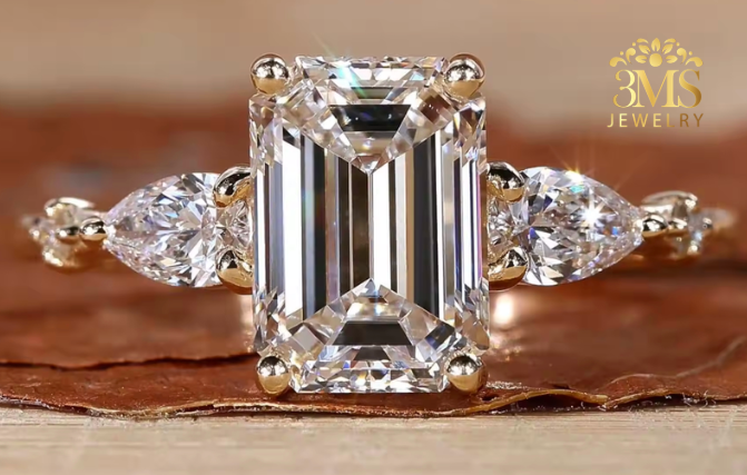 "Lab diamond emerald-cut engagement ring in three-stone design and 14K yellow gold settings—a close-up view."