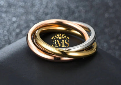 Three interlocked rings in rose gold, white gold, and yellow gold on a dark textured background
