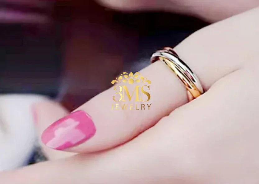 Close-up of a hand with pink nail polish wearing a two-tone gold and silver love ring