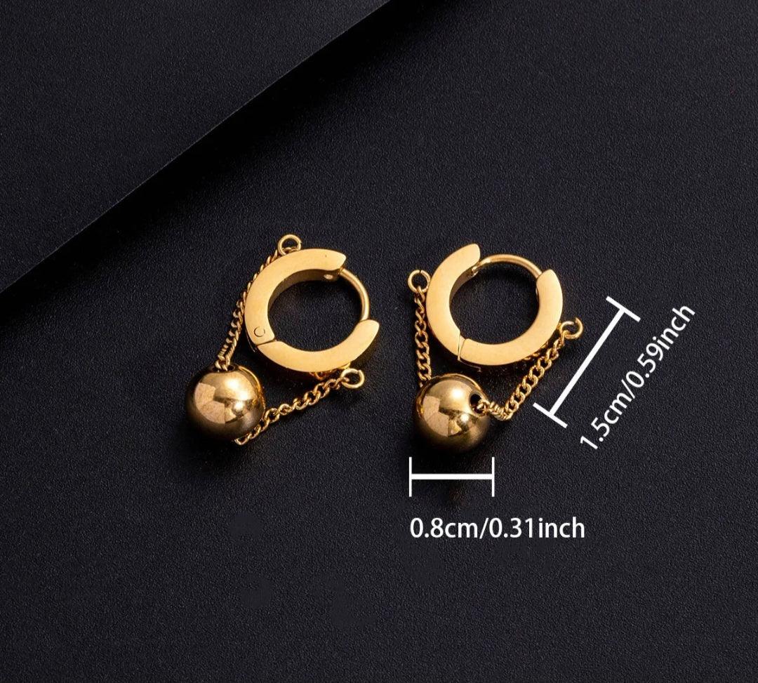 Gold hoop earrings with dangling gold ball charms on black background with size dimensions