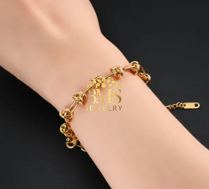 Gold knot link bracelet on wrist with adjustable chain clasp against black background