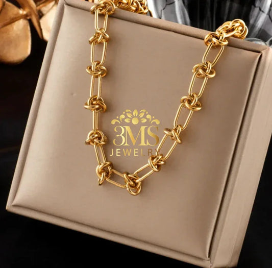Gold chain necklace with knotted details displayed on beige jewelry box from 3MS Jewelry