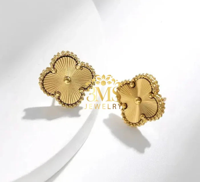Gold clover-shaped stud earrings with textured center and beaded edge on white background