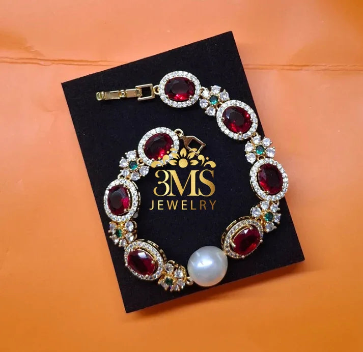Elegant ruby bracelet with oval red gemstones, sparkling diamonds, green accents, and a large pearl on black box