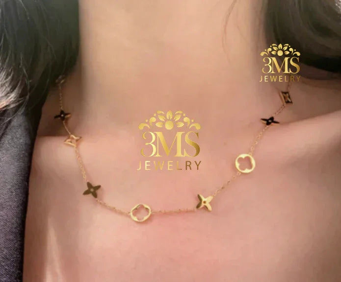 Delicate gold necklace with floral and geometric charms worn on neck