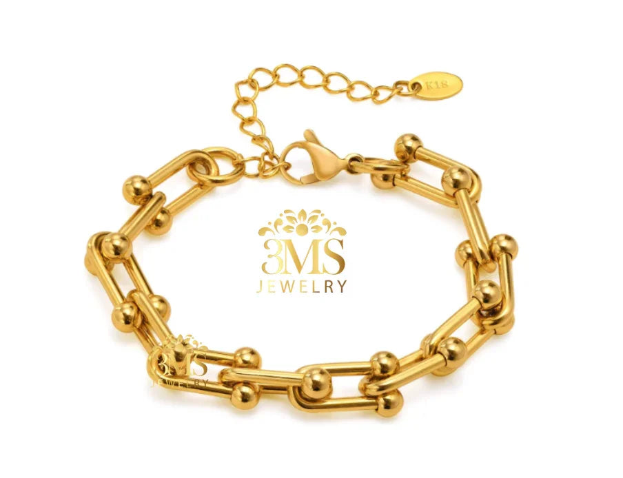 Gold link bracelet with spherical accents and adjustable chain clasp on white background