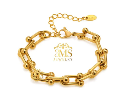 Gold link bracelet with spherical accents and adjustable chain clasp on white background