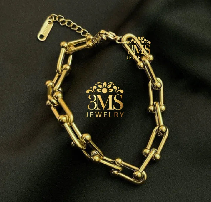 Gold link bracelet with spherical accents on black fabric background by 3MS Jewelry