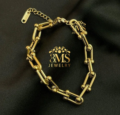 Gold link bracelet with spherical accents on black fabric background by 3MS Jewelry