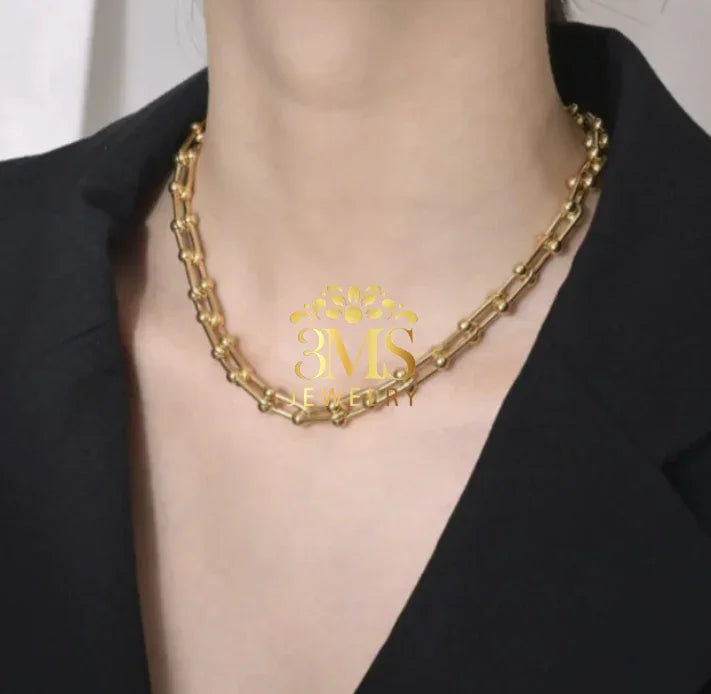 gold chain necklace with textured links worn with black blazer on neck