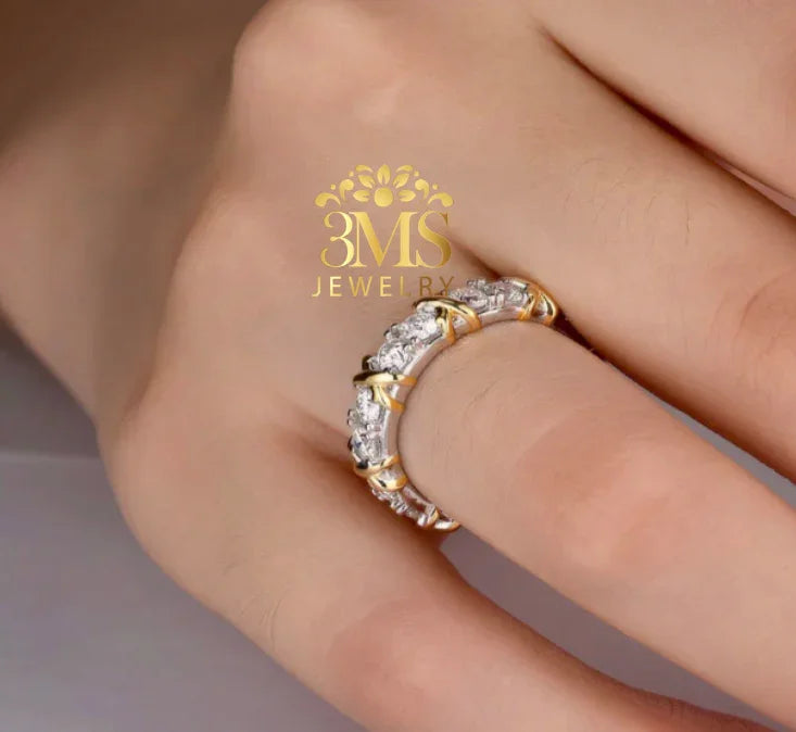Close-up of hand wearing a gold and silver diamond eternity ring with cross prong setting