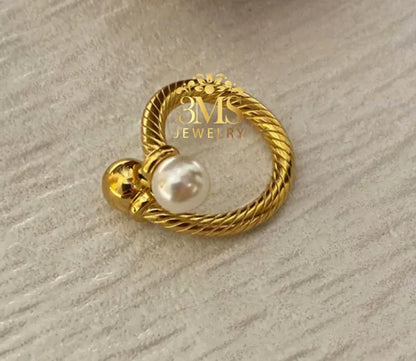 Gold twisted ring with a white pearl and a gold bead on textured surface by 3MS Jewelry