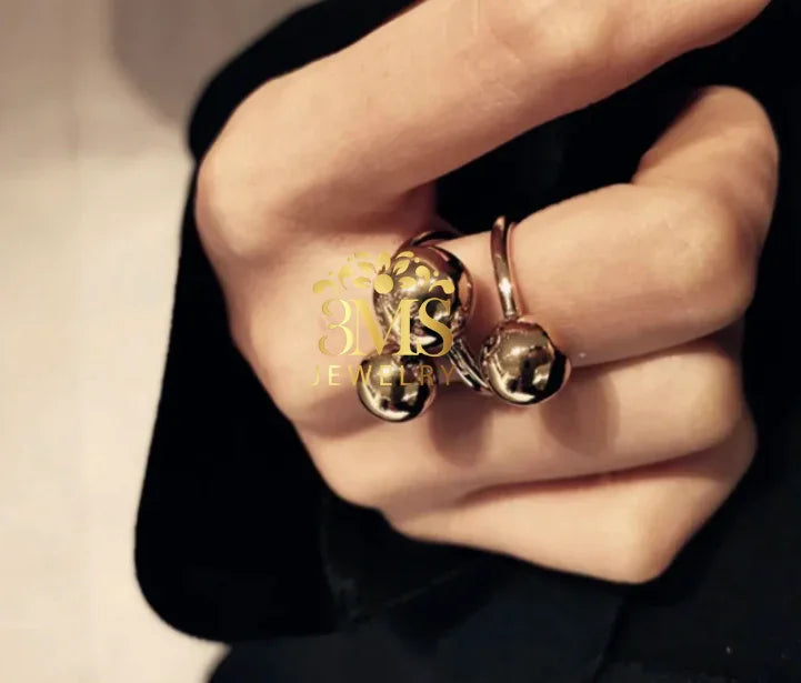 Close-up of hand wearing stylish silver rings with spherical designs on black fabric background